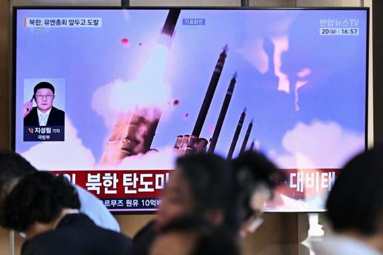 Des personnes sont assises près d'un écran TV diffusant un bulletin d'information avec des images d'archives d'un essai de missile nord-coréen, le 20 septembre 2026 dans une gare de Séoul