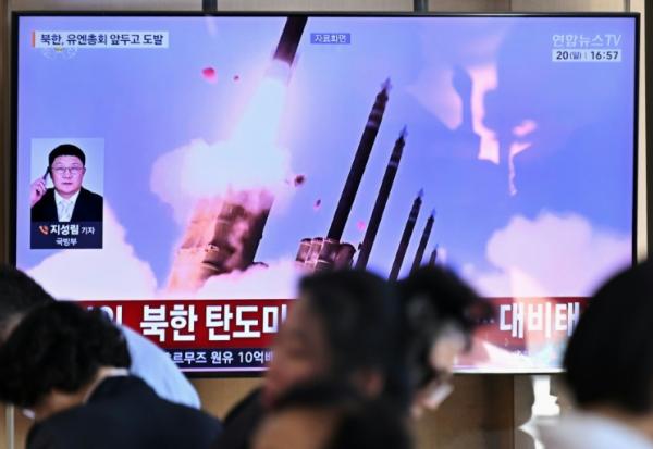 Des personnes sont assises près d'un écran TV diffusant un bulletin d'information avec des images d'archives d'un essai de missile nord-coréen, le 20 septembre 2026 dans une gare de Séoul
