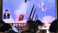 Des personnes sont assises près d'un écran TV diffusant un bulletin d'information avec des images d'archives d'un essai de missile nord-coréen, le 20 septembre 2026 dans une gare de Séoul