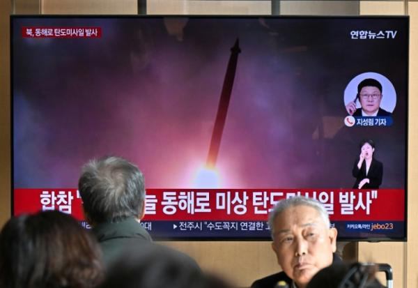 Des passants regardent une télévision diffusant un journal télévisé avec des images d'archives d'un essai de missile nord-coréen, dans une gare de Séoul, le 7 novembre 2025