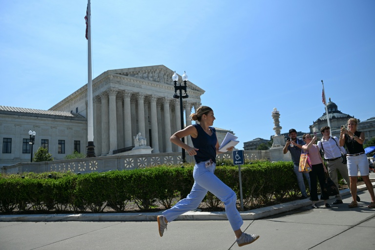 Une journaliste court devant la Cour suprême des États-Unis après qu'elle a rejeté la tentative du président Donald Trump de restreindre l'acquisition de la citoyenneté par le droit du sol, le 30 juin 2026 à Washington