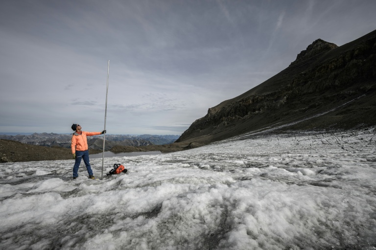 Le glaciologue Matthias Huss brandit une perche de mesure de quatre mètres de long, équivalant à la hauteur de la couche de glace ayant fondu en un an, le 24 septembre 2024 sur le glacier du Scex Rouge, en Suisse