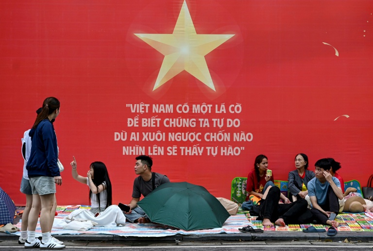 Des gens attendent et campent sur les trottoirs le 1er septembre 2025 à Hanoï avant le défilé militaire prévu mardi