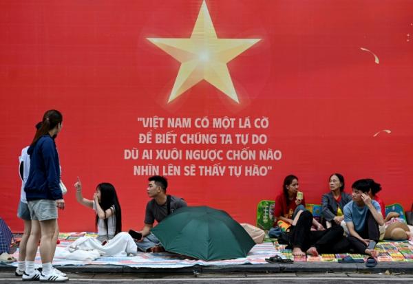 Des gens attendent et campent sur les trottoirs le 1er septembre 2025 à Hanoï avant le défilé militaire prévu mardi
