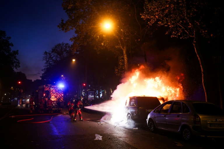 Les pompiers éteignent un véhicule en feu à Paris, lors de la manifestation contre la 