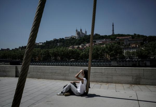 Une personne est assise sur les quais de la Saône, à Lyon, le 26 mai 2026, alors qu'une vague de chaleur frappe la France