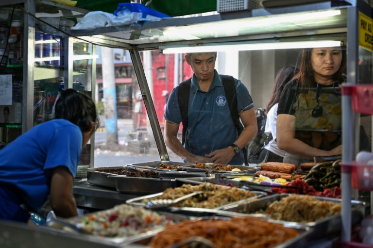 Des gens achetant de quoi manger dans une cantine de rue à Manille, le 7 avril 2026