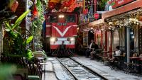 Un train passe au ras des cafés et des habitations dans la célèbre et touristique "rue du train" à Hanoi, le 18 août 2025 