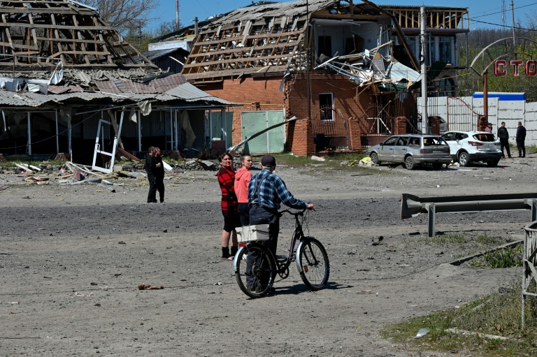 Des habitants de Merefa, dans l'est de l'Ukraine, passent près de bâtiments et de voitures endommagés par une frappe de missile russe, le 4 mai 2026