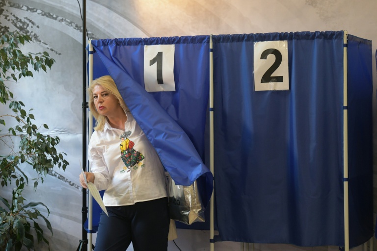 Une femme sort d'un isoloir après avoir voté aux élections législatives russes dans un bureau de vote de Donetsk, dans l'est de l'Ukraine sous contrôle russe, le 18 septembre 2026