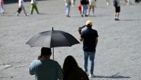 Des touristes visient Bruxelles à l'abri sous un parapluie pour se protéger du soleil lors d'une vague de chaleur le 27 mai 2026, en Belgique