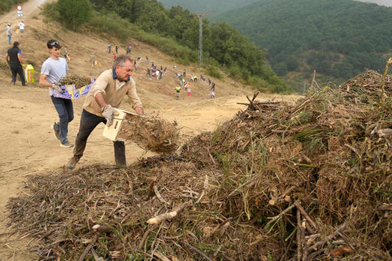 Des habitants réalisent des travaux de déboisement en prévision d'un possible arrivée du feu provenant de l'incendie du parc national des Picos de Europa, dans la ville de Riano, en Castille-et-León, en Espagne, le 18 août 2025