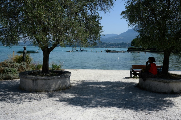 Une femme s'abrite du soleil à l'ombre d'un arbre sur une rive du lac du Bourget, au Bourget-du-Lac, en Savoie le 8 août 2025