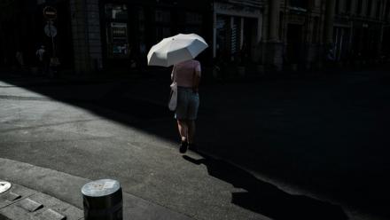 Une femme marche sous un parapluie pour se protéger du soleil lors d'une vague de chaleur à Lyon, dans le Rhône, le 24 juin 2026