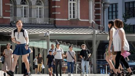 Des passants devant la gare de Tokyo un jour de chaleur le 27 août 2025