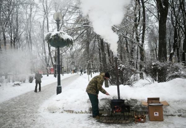 Un bénévole ukrainien cuisine un pain traditionnel d'Asie centrale dans un parc de Kiev, le 15 janvier 2026 
