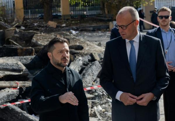 Le président ukrainien Volodymyr Zelensky (G) et le chancelier allemand Friedrich Merz (D) lors d'une visite du bâtiment endommagé de l'Académie des sciences de Kiev, le 4 octobre 2026 
