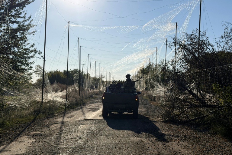 Un soldat de la 141e brigade mécanisée autonome ukrainienne se déplace à bord d'un pick-up sous le filet anti-drones dans le village de Prosyana, dans la région de Dnipropetrovsk, le 2 octobre 2026