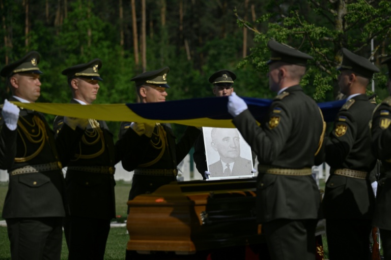 Des militaires de la garde d’honneur ukrainienne tiennent des drapeaux nationaux au-dessus des cercueils contenant les dépouilles d’Andriy Melnyk, mort en 1964 et chef d’une branche de l’Organisation des nationalistes ukrainiens (OUN) lors de leur cérémonie de réinhumation au cimetière militaire national près de Kiev, le 25 mai 2026