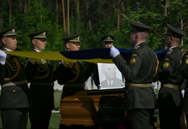 Des militaires de la garde d’honneur ukrainienne tiennent des drapeaux nationaux au-dessus des cercueils contenant les dépouilles d’Andriy Melnyk, mort en 1964 et chef d’une branche de l’Organisation des nationalistes ukrainiens (OUN) lors de leur cérémonie de réinhumation au cimetière militaire national près de Kiev, le 25 mai 2026