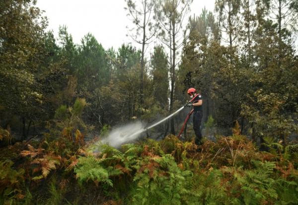 Un pompier arrose de la végétation pour empêcher les reprises de feu, le 16 août 2026 à Luglon, dans les Landes 