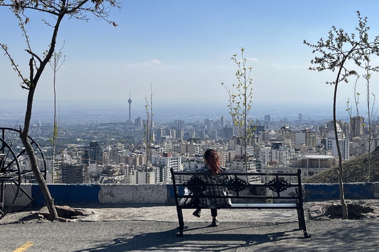 Une femme est assise sur un banc donnant sur la ville, au parc Pardisan à Téhéran, le 22 avril 2026.