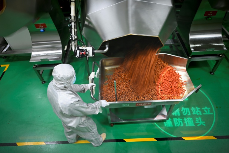 Un employé prépare des lamelles épicées pour leur conditionnement à l'usine Mala Wangzi du comté de Pingjiang, dans la province du Hunan, le 17 juin 2026 dans le centre de la Chine