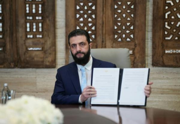 Le président syrien Ahmad al-Chareh montre un accord de cessez-le-feu signé à distance avec le chef des forces kurdes, le 18 janvier 2026 au palais présidentiel de Damas.

