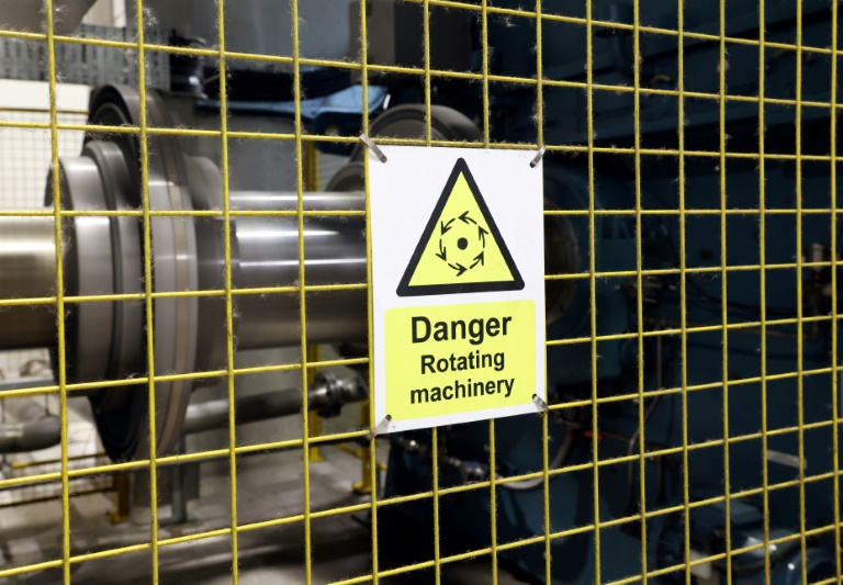 Un panneau d'avertissement devant une grille protégeant l'accès à un système de volant d'inertie dans les locaux du géant énergétique norvégien Statkraft, le 7 août 2025 à Liverpool