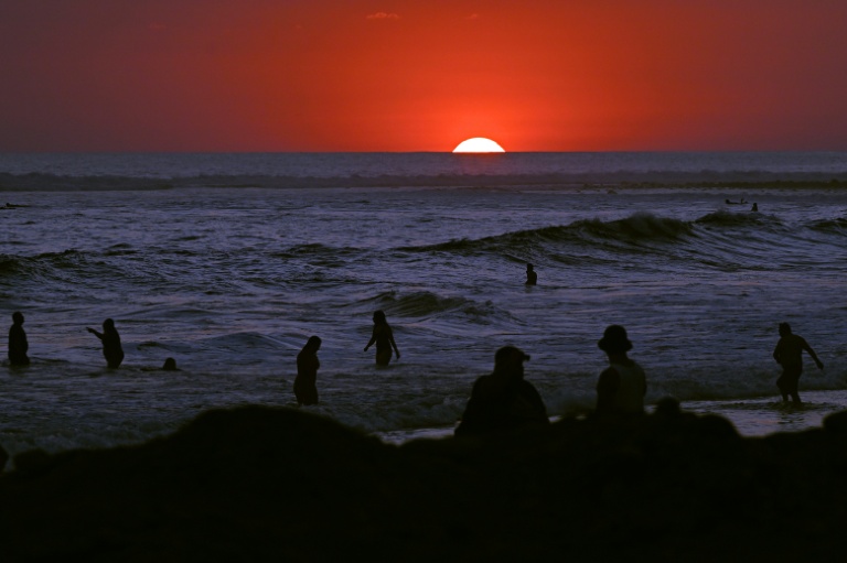 Des touristes se baignent au soleil couchant sur la plage d'El Tunco, à La Libertad, au Salvador, le 13 février 2026
