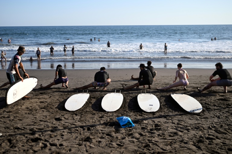 Des touristes suivent des cours de surf à la plage d'El Tunco, à La Libertad, au Salvador, le 13 février 2026