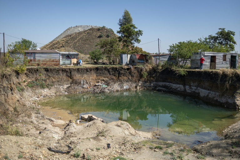 Des habitations surplombent une fosse à ciel ouvert creusée par des mineurs illégaux à la recherche de chrome à Bapong, un village minier de la province du Nord-Ouest (Afrique du Sud), le 25 août 2026