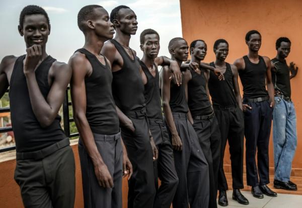 Des jeunes mannequins écoutent les instructions d'un coach pour apprendre à défiler, sur le toit des bureaux de l'agence Jubalicious à Juba, le 20 février 2026 au Soudan du Sud