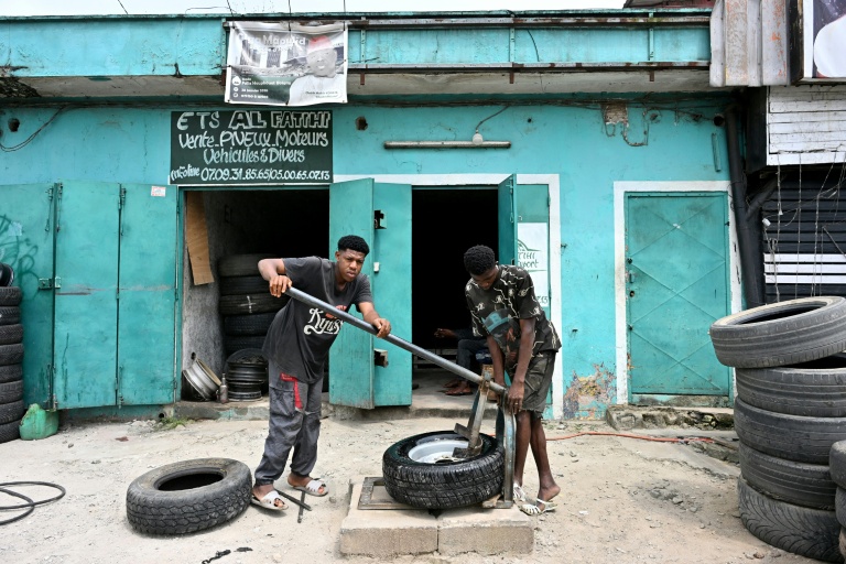 Des monteurs de pneus informels posent des pneus d’occasion dans la rue à Abobo, dans la banlieue d’Abidjan, la capitale économique ivoirienne, le 21 juillet 2026.