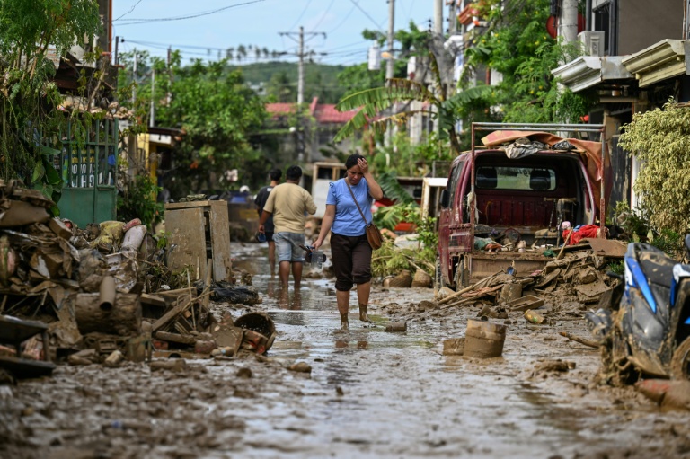 Des habitants dans une rue recouverte de boue après le passage du typhon Kalmaegi à Liloan, dans la province de Cebu, le 6 novembre 2025 aux Philippines