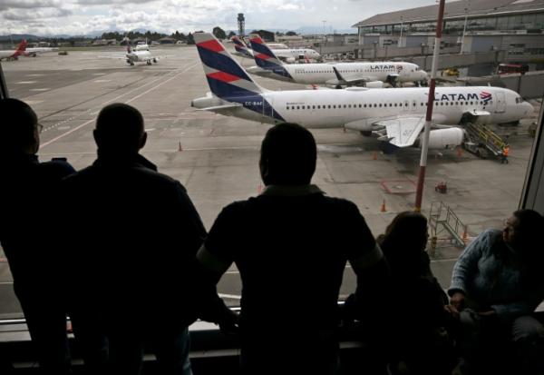 Des passagers vénézuéliens regardent des avions de la compagnie LATAM après l'annulation de leur vol pour Caracas, le 19 mai 2025 à l'aéroport El Dorado de Bogota
