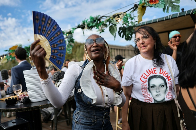 Des fans de la chanteuse canadienne Céline Dion portant des accessoires -éventail, T-shirt, etc. à son effigie- participent à une croisière hommage à leur idole sur la Seine à Paris, le 13 septembre 2026