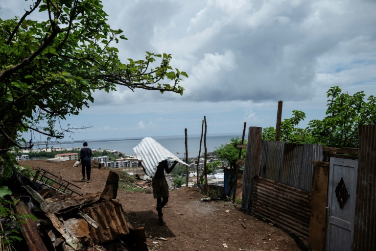 Un homme transporte une feuille de tôle dans le bidonville de Cavani, à Mamoudzou, à Mayotte, le 2 janvier 2025