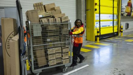 Un employé pousse un conteneur de colis dans un entrepôt DHL à Lesquin, près de Lille, le 12 novembre 2025