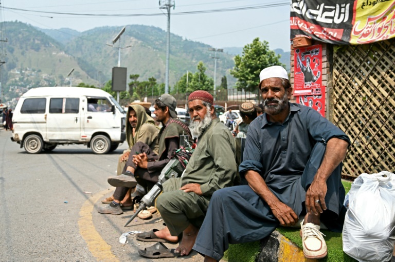 Des ouvriers journaliers assis au bord de la route en attendant d'être transportés vers des sites de construction par des employeurs, à Muzaffarabad, le 1er mai 2025 au Cachemire pakistanais
