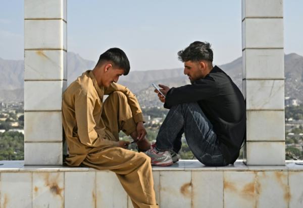 Des jeunes Afghans consultent leurs smartphones, sur la colline de Wazir Akbar Khan, à Kaboul, le 10 août 2026