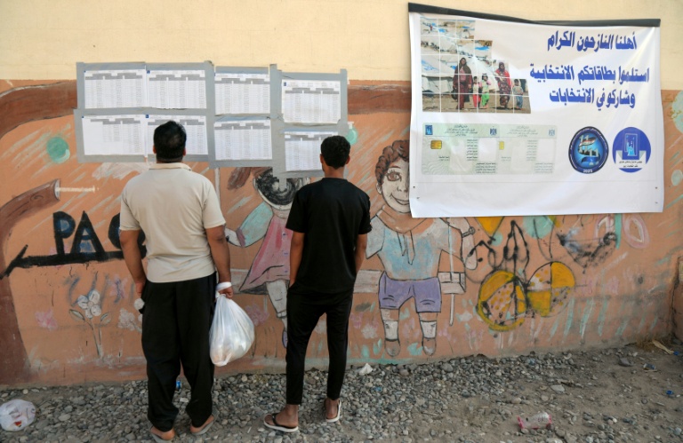 Des Irakiens déplacés consultent les listes nominatives affichées à l'extérieur d'un bureau de vote, à l'arrivée pour voter avant les élections législatives du 11 novembre, dans un camp du nord de l'Irak, le 9 novembre 2025