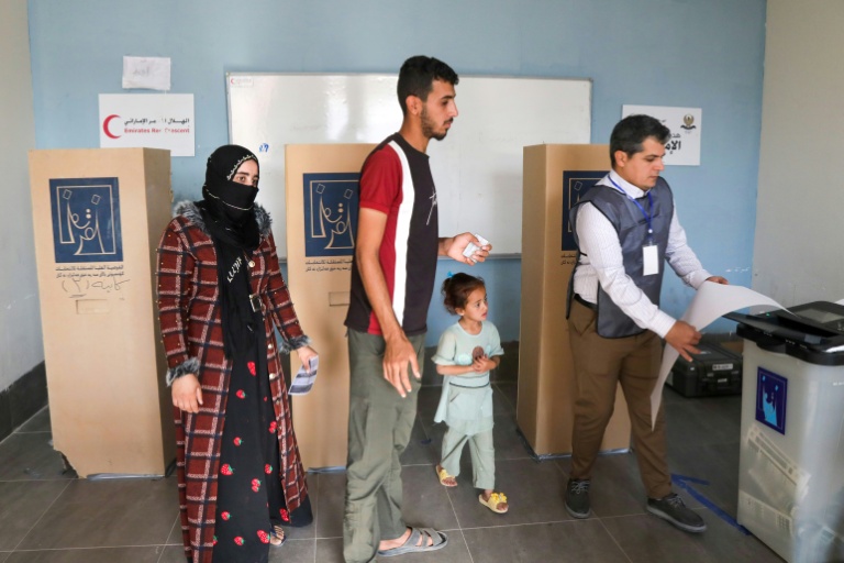 Un Irakien déplacé reçoit de l'aide pour voter dans un bureau de vote avant les élections législatives du 11 novembre, dans un camp du nord de l'Irak, le 9 novembre 2025