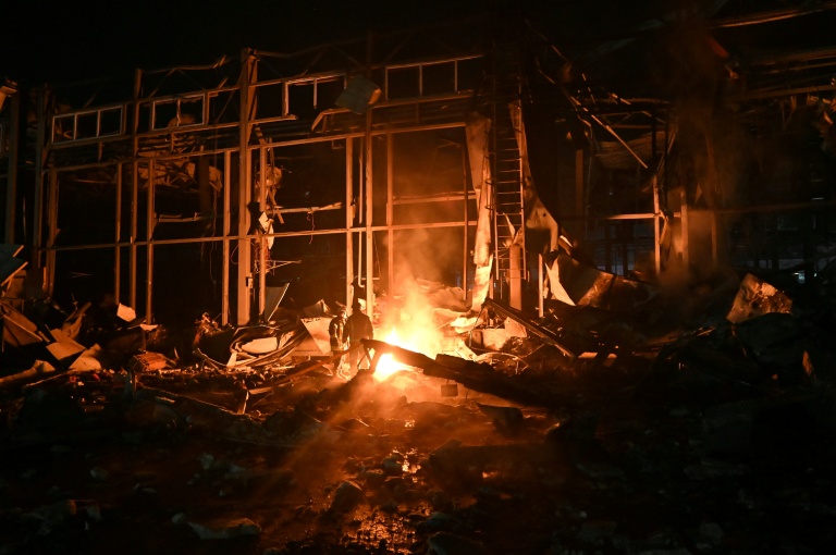 Des pompiers luttent contre un incendie provoqué par un bombardement russe sur un entrepôt de la compagnie des postes Nova Pochta dans un village près de Kharkiv, le 13 janvier 2026 en Ukraine