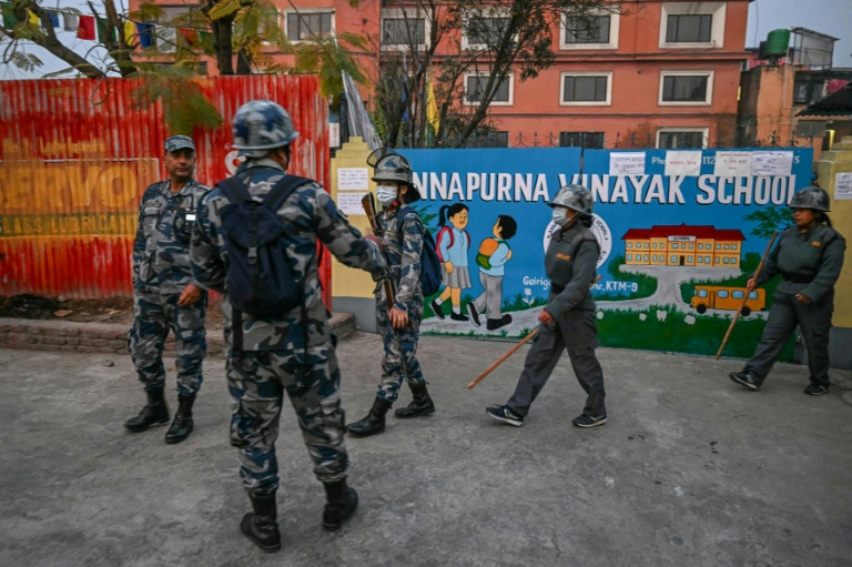 Des agents de sécurité se rassemblent devant un bureau de vote avant l'ouverture des urnes lors des élections législatives népalaises à Katmandou, le 5 mars 2026