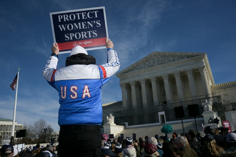 Un homme tient une affiche contre la participation des personnes transgenres aux compétitions sportives féminines devant la Cour suprême américaine, à Washington, le 13 janvier 2026