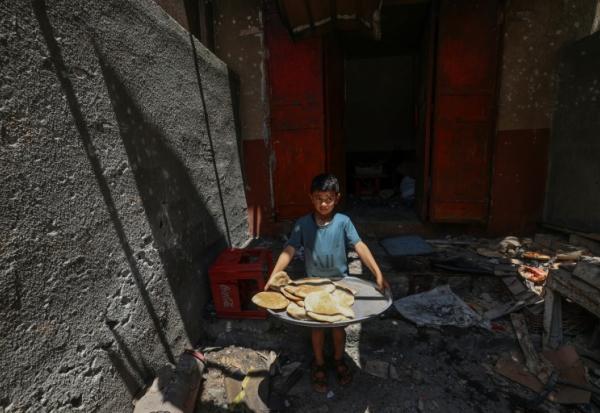 Un garçon palestinien sort avec du pain d'une boulangerie de fortune touchée par des frappes israéliennes dans le camp de réfugiés de Nusseirat, dans le centre de la bande de Gaza, le 8 mai 2025
