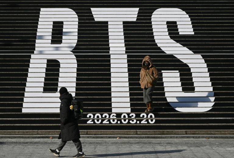 Des piétons le long d'escaliers décorés du logo du groupe de K-pop BTS, près de la place Gwanghwamun à Séoul, le 14 janvier 2026