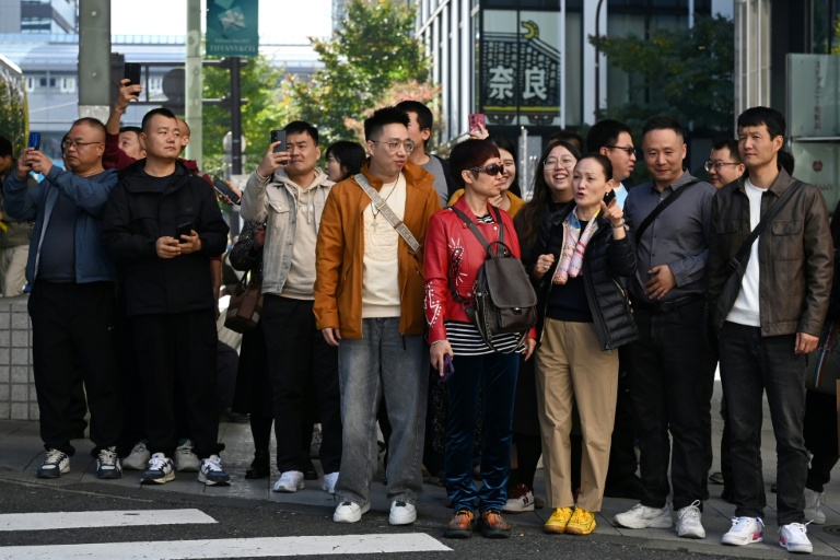 Un groupe de touristes chinois attend pour traverser une rue dans le quartier commerçant de Ginza, à Tokyo, le 16 novembre 2025