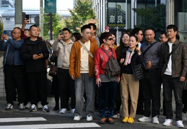 Un groupe de touristes chinois attend pour traverser une rue dans le quartier commerçant de Ginza, à Tokyo, le 16 novembre 2025